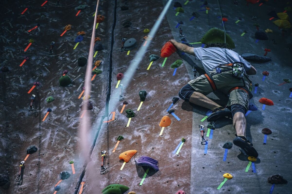 Athletes climb rock wall and